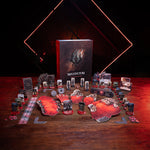 a collection of board game components, including a box, various cards, and other game pieces, arranged on a wooden surface. The background features a dark, dramatic lighting that creates a moody atmosphere.